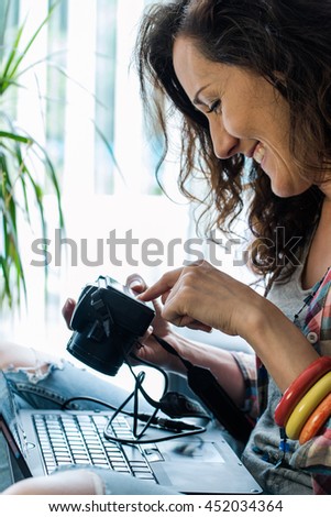 happy woman check photos on camera while sitting on sofa