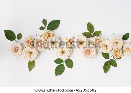 Pink and tea roses and green leaves isolated on white background. Flat lay, top view.