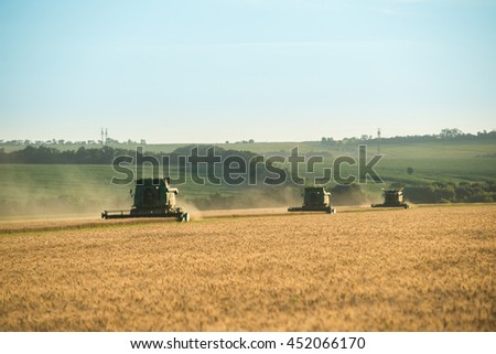 Three modern combine harvester working on a wheat crop