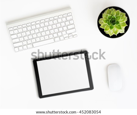 White office desk table with tablet pc computer in ipade style with blank screen, wireless aluminum keyboard, mouse and succulent flower in pot. Top view with copy space. Flat lay. Royalty-Free Stock Photo #452083054