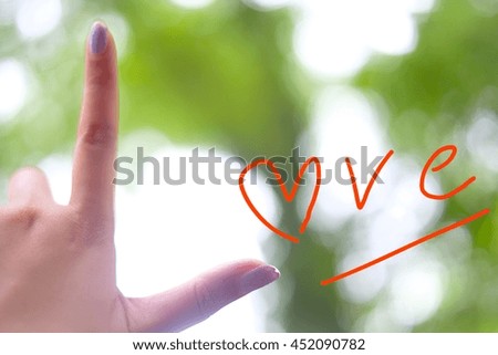 Hand shape showing of love on blurred abstract cool green color bokeh background.