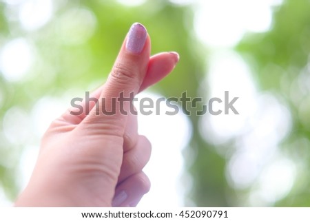 Hand shape showing of love on blurred abstract cool green color bokeh background.