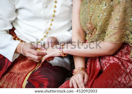 Groom put a ring on finger of his lovely wife. Thai style