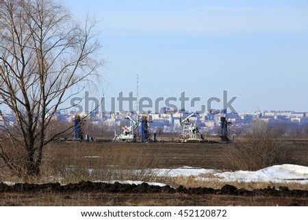 oil pumps in the field on a background of the city on the horizon in early spring
