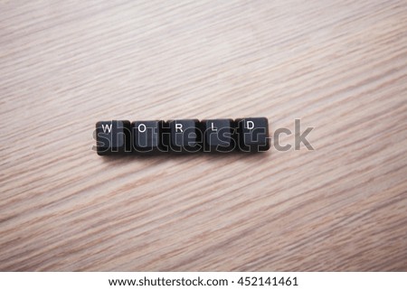 Five black buttons on the computer keyboard with the word WORLD on a wooden background
