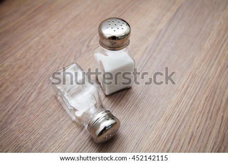 Salt shaker with salt and white pepper on the empty wooden kitchen table