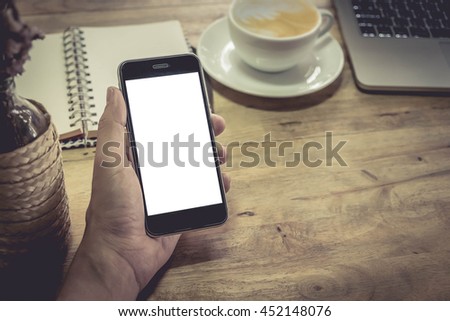 Close up of a man hand using smartphone with blank screen mobile and cup of coffee.