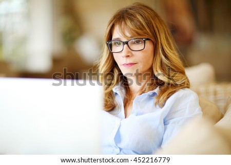 Close-up portrait of confident middle aged businesswoman using her laptop while working at home. 