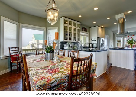 Classic American dining area connected to kitchen. Old wooden table set with nice tablecloth