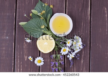 Organic essential aroma oil with lemon and herbs on aged wooden background. 