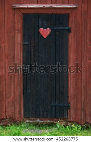 Traditional vintage restroom or lavatory outside with a heart sign on the black door. Sweden