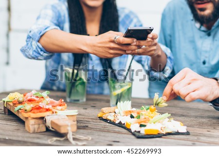 Young couple sitting in the restaurant and taking pictures of the food with mobile phone
