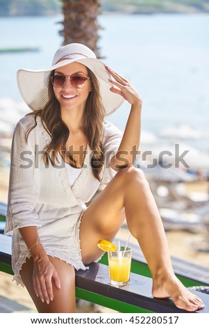 Beautiful young woman drinking juice on beach