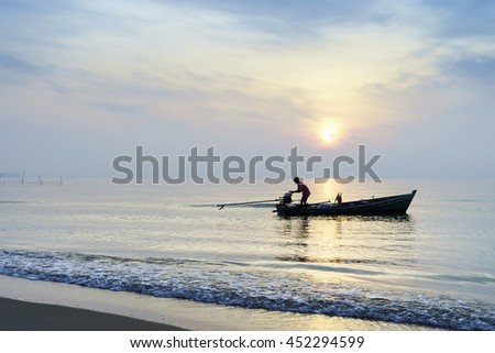 silhouette fisherman working on boat at sea with sunrise background,select focus with shallow depth of field
