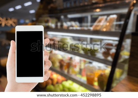 woman use mobile phone and blurred image of product showcase of fruit and juice shop