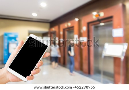 woman use mobile and blurred image of women wait for elevator in hotel