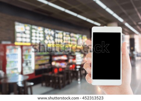 woman use mobile phone and blurred image of cafe shop 