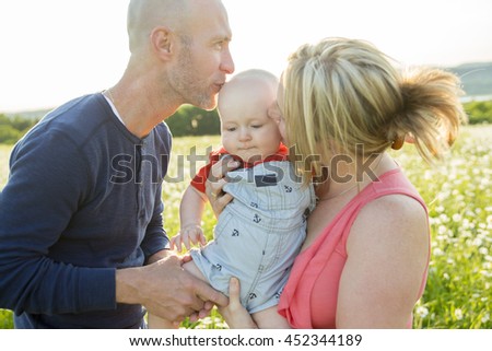 happy family of three. Father, mother and baby playing outside in summer at sunset time.