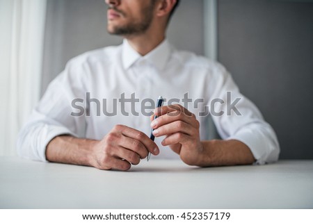 Business Closeup portrait of handsome businessman hands with a pen. Thinking and looking on the window.