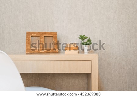 Home interior decor, bouquet of lilacs in a vase,picture frame and books on rustic wooden table, on wallpaper background.