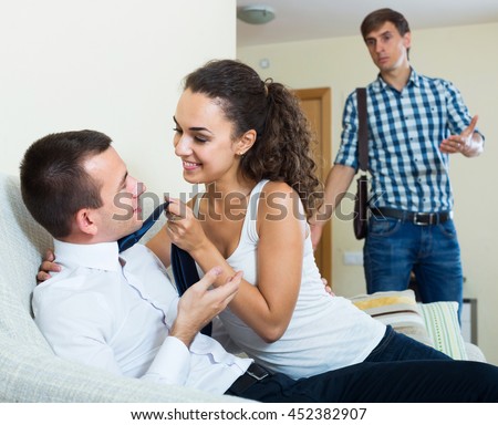 Love triangle: adult husband, happy russian wife and lover at domestic interior Royalty-Free Stock Photo #452382907