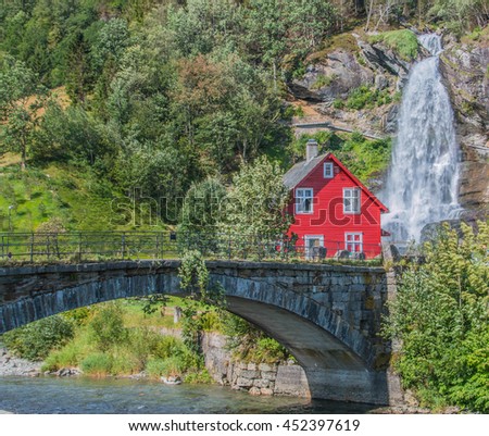 Red wooden House in front of Steinsdalsfossen Waterfall in Norway Royalty-Free Stock Photo #452397619