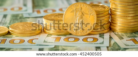 Stack of golden eagle coins on new design of US currency one hundred dollar bills with spotlight on the Liberty statue on one coin. Sized for cover photo image on popular social media site