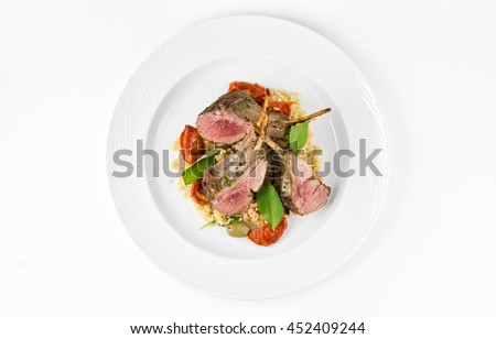 Rack of lamb with bulgur, dried tomatoes and lemon Moroccan on a plate on a white background, top view Royalty-Free Stock Photo #452409244