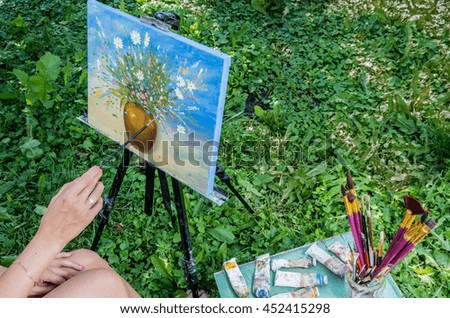 The hands of the artist, who paints in oil on the open air.