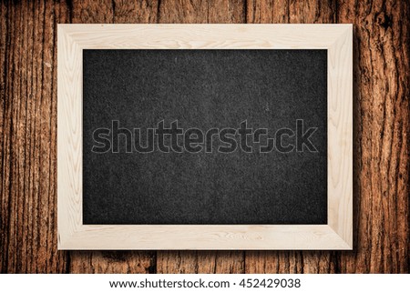 Blank chalkboard in wooden frame on old wooden background