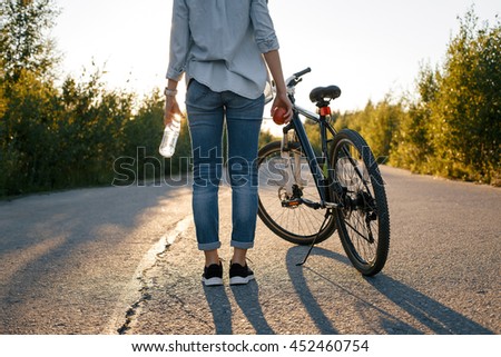 girl standing next to the bike back on the road in the summer