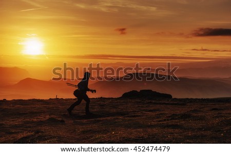 Happy man standing on a cliff at sunset.

