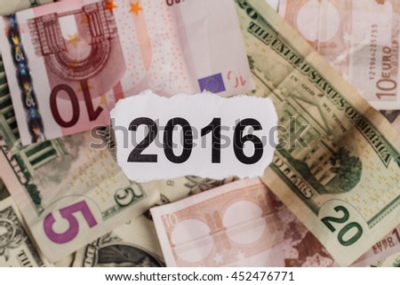 Focus on the words 2016 on piece of torn white paper with USD
dollars and EURO currency as a background. Concepts of investment and business.