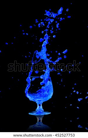 Drink Cocktail blue splash out of glass on a black background.
