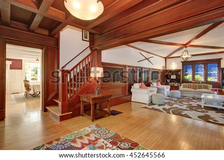 Luxury Living room interior with wooden walls, hardwood floor and vaulted ceiling. View of wooden staircase and dining room.