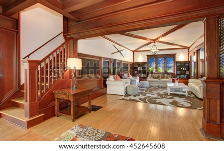Luxury Living room interior with wooden walls, hardwood floor and vaulted ceiling. View of wooden staircase leading upstairs..