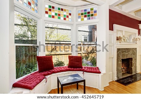  Cozy sitting area with wide decorative windows and red pillows. View of fireplace with stone decor.