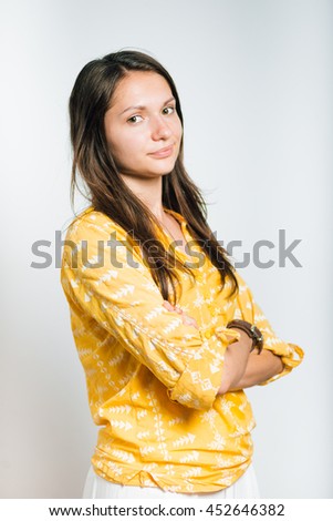 Pretty girl looks at you with her hands folded crosswise isolated on a gray background