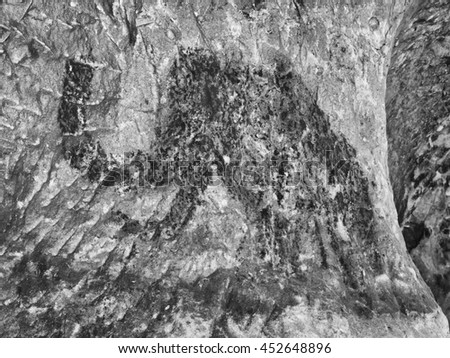 Abstract children art in sandstone cave. Black carbon mammoth paint of human hunting on sandstone wall, copy of prehistoric picture. Sandstone structure.
