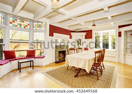 Bright dining room in red walls and white wooden trimmings. Also fireplace with stone decor and sitting area with wide window.