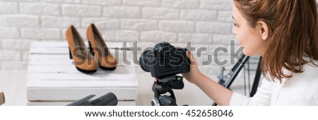 Panoramic photo of a young photographer taking shots of high heels in a bright atelier