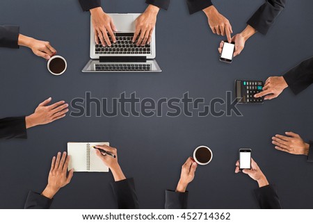 Office desk mockup with hand using/holding laptop, smart phone, notebook, calculator and cup of coffee on gray color background. View from above. Flat lay photo/copy space with business concept.