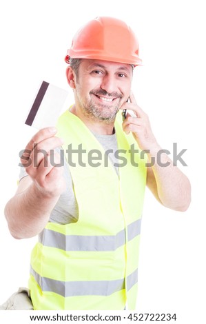Handsome constructor talking on phone and holding credit card as construction services payment concept isolated on white