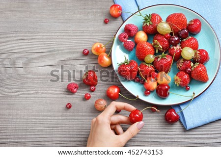 Ceramic plate with cherries, strawberries and raspberries at old wooden table. Close up, high resolution product. Harvest Concept
