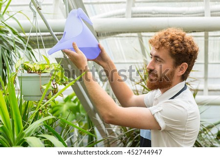 Surrounded by nature. Portrait of a mature man watering a plant in his greenhouse