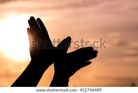 Raised hands catching sun on sunset sky. Concept of freedom