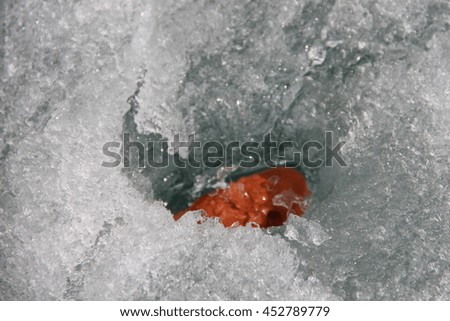 Red Stone in the ice. Picture taken at Lake Baikal, Russia.