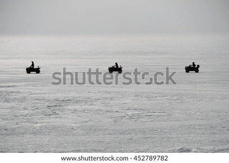 Three hikers on a quad (motorbike) rides on the ice. Picture taken at Lake Baikal, Russia.