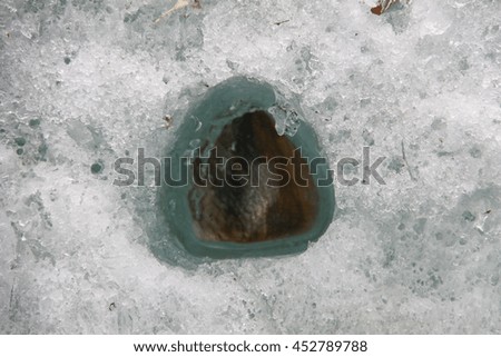 dark gray stone in the ice. Picture taken at Lake Baikal, Russia.