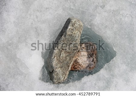 Two light gray stone in the ice. Picture taken at Lake Baikal, Russia.